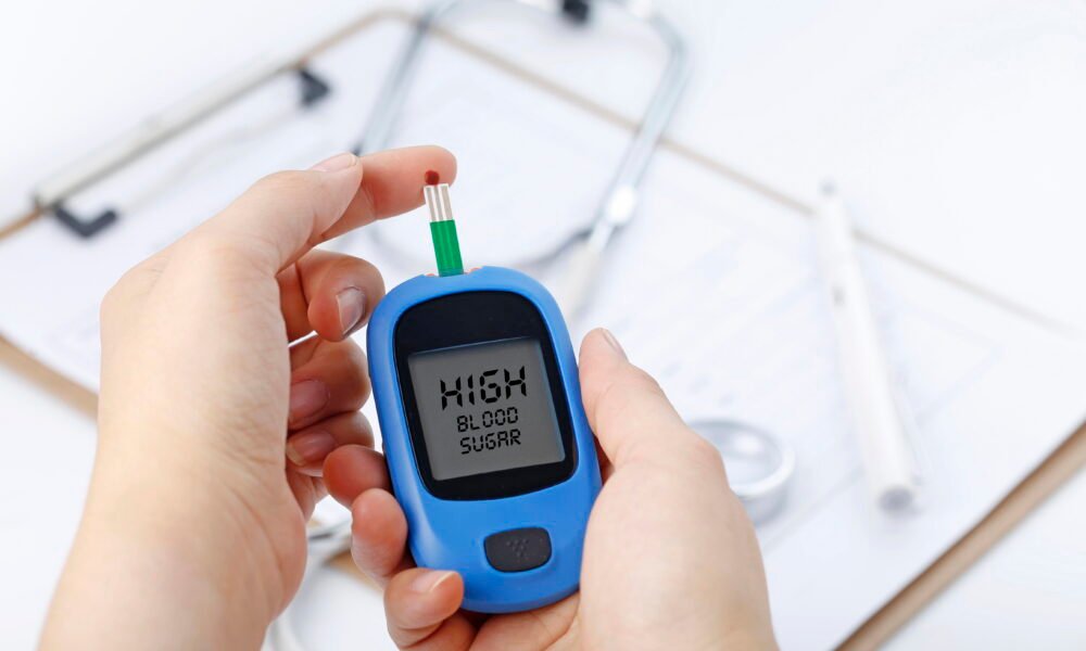 hand holding blood glucose meter measuring blood sugar background is stethoscope chart file